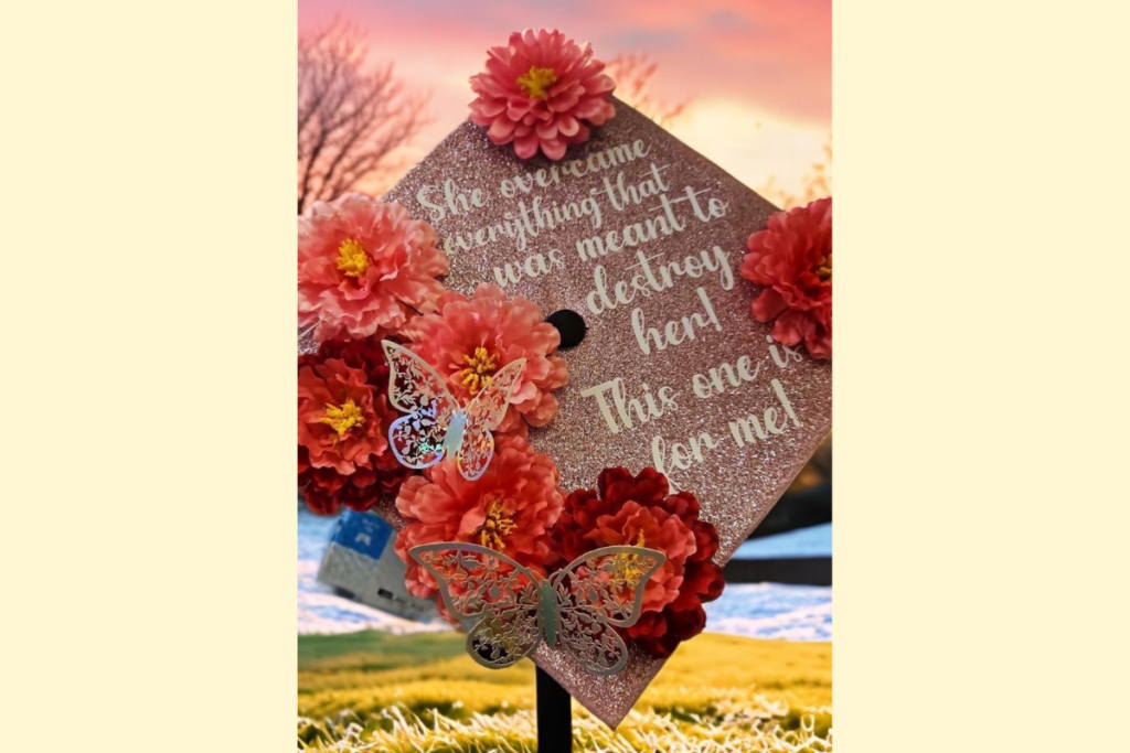 Pink glittered graduation cap adorned with pink flowers. Text reads: She overcame everything that was meant to destroy her! This one is for me!